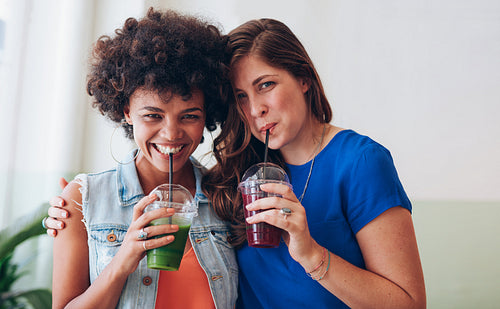 Happy young friends drinking fresh fruit juice together