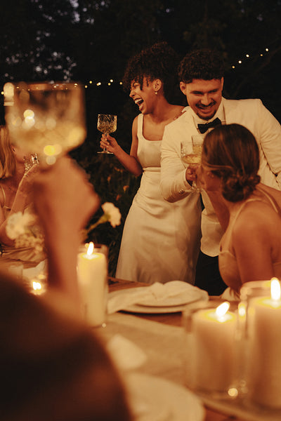Wedding couple celebrating at a candlelit outdoor reception with friends