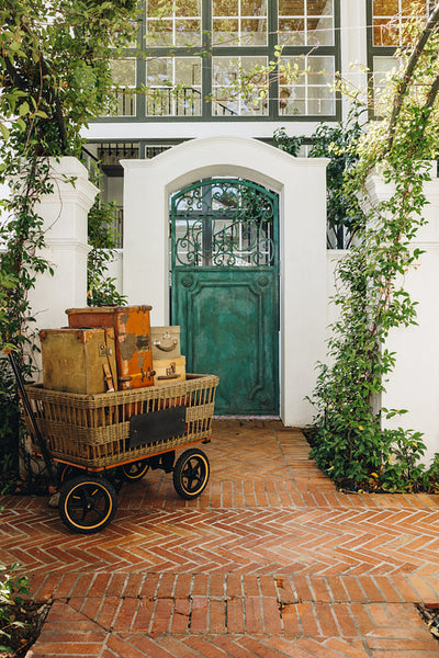 Trolley cart full of vacation bags in front of a hotel entrance