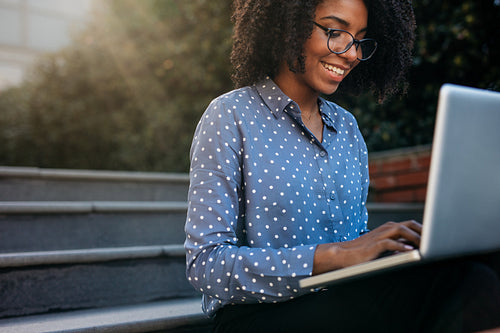 Businesswoman sitting on steps outdoors working on laptop