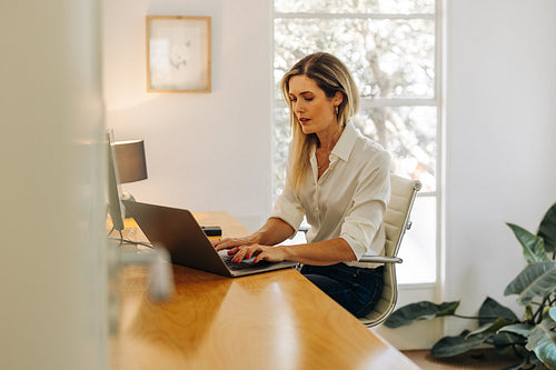 Focused businesswoman typing on a laptop in her office
