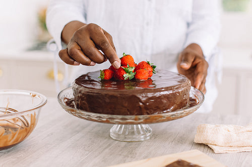 Close-up of a woman decorating cake with strawberries