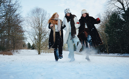 Walking through snow, women share laughter at the park