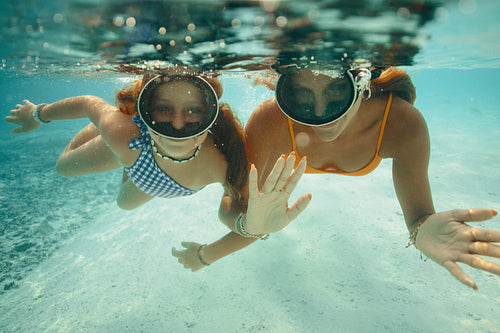 Oceanic adventure: Mother and daughter snorkelling, sharing joy in clear blue waters