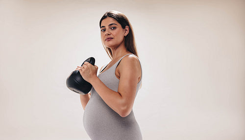 Expecting mother exercising with a dumbbell for a healthy pregnancy