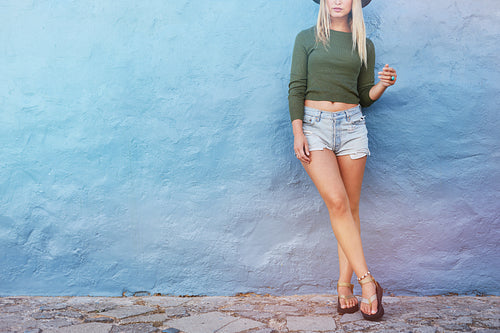 Fashion hipster woman posing near blue wall