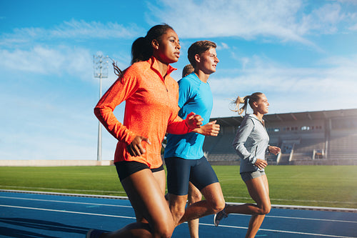 Runners running on race track in stadium