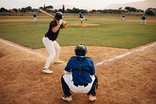 Baseball game in action with pitcher, batter, and catcher on a sunny day at the field