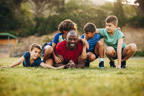 School coach and his team lying in a sports field