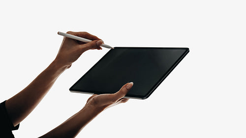 Hands holding a tablet and stylus for digital writing or sketching