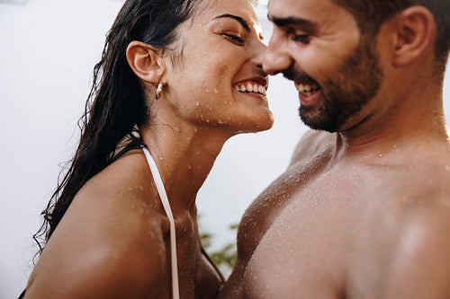 Smiling couple flirting under an outdoor shower