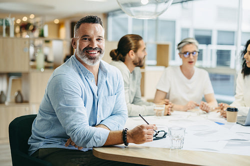 Happy businessman sitting in a meeting with his colleagues