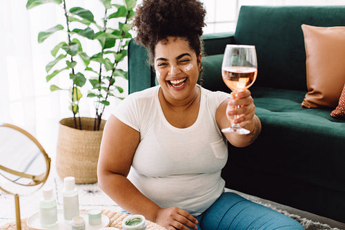 Woman toasting wine with cream on face