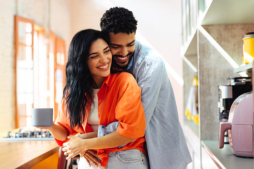 Happy Latin American couple sharing a joyful moment in their modern kitchen