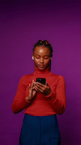 Young black woman with braids dances to music on her phone