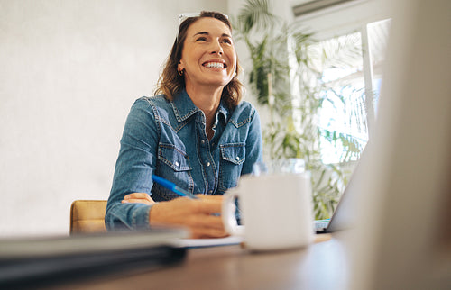 Successful businesswoman writing at her office desk