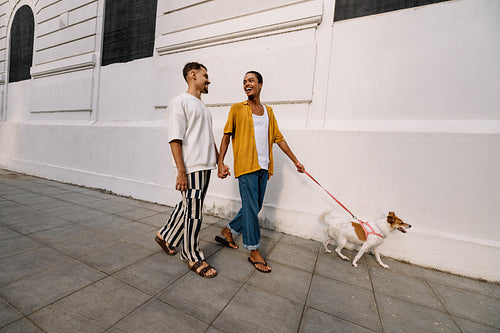 Couple walking happily with their dog along a city street