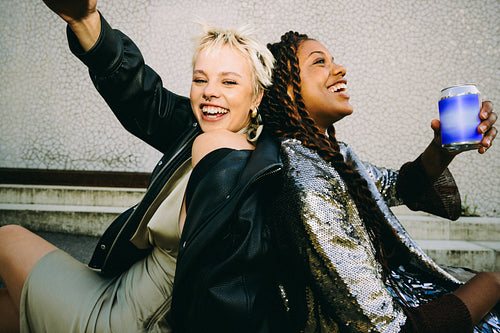 Drinks with friends: young women laughing on outdoor steps