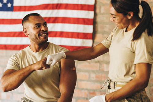 Happy young soldier fist bumping a nurse after getting vaccinate