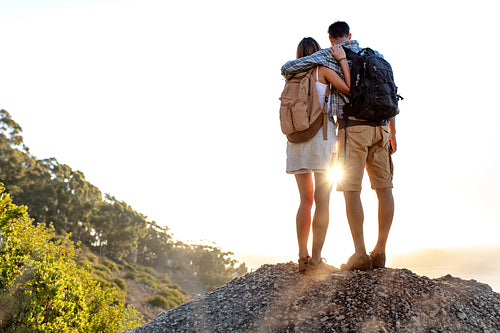 Hiking couple standing on a rock admiring the view