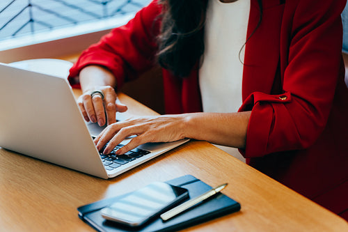 Professional hands typing on a laptop at a wooden desk during work