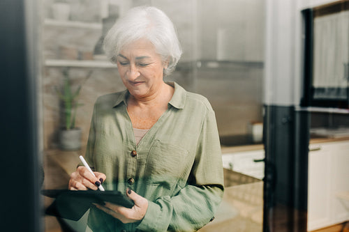 Senior woman signing a digital document at home