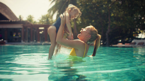 Mother and daughter share happy moments playing and laughing together in a resort swimming pool