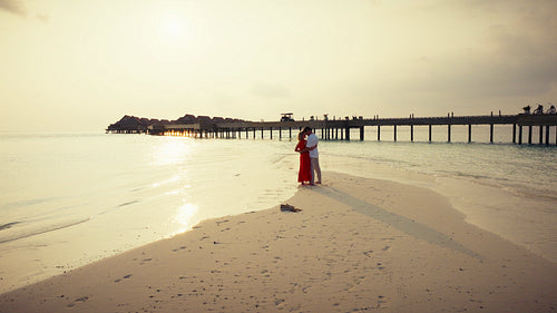 A loving couple shares a tranquil moment on a secluded beach at golden hour