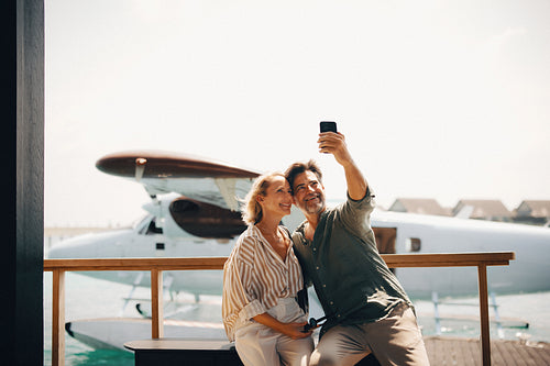 Happy couple posing for selfie on seaplane dock