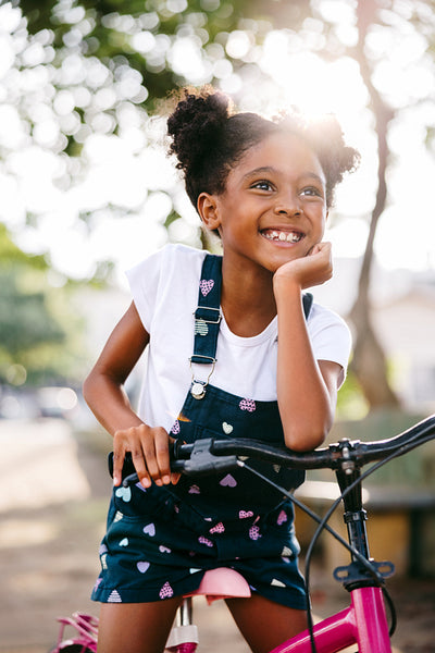 Happy young girl smiling while sitting on a pink bicycle