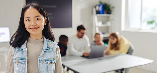 Happy female student standing in a coding classroom, looking at the camera with a smile