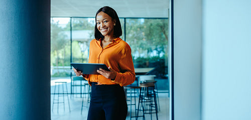 Confident female lawyer holding tablet in modern office