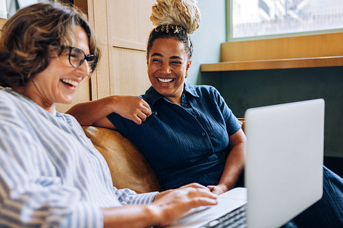 Two women smiling and enjoying a productive discussion with a laptop in view