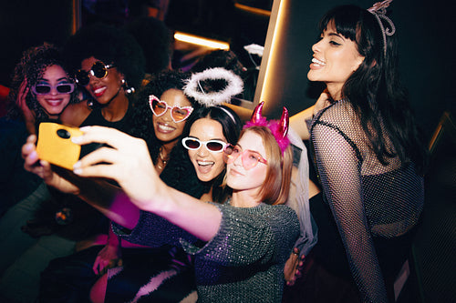 Group of joyful friends taking a selfie during a costume party celebration