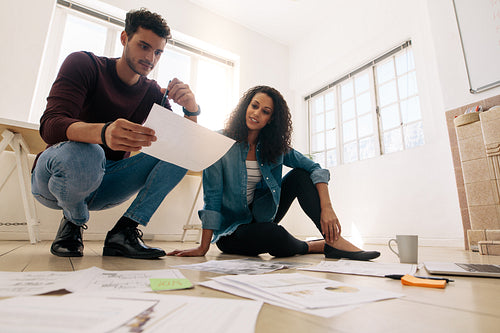 Business partners sitting on the floor and working with business papers spread on the floor