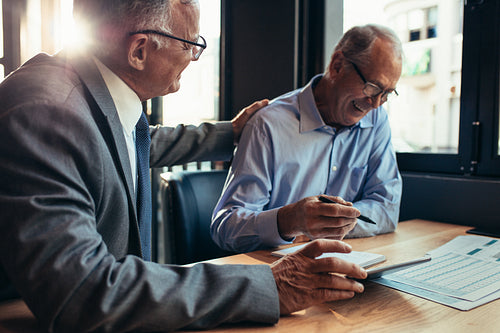 Smiling senior businessmen working together at cafe