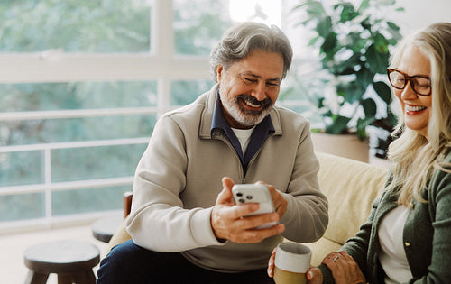 Senior couple explore the internet together on a sofa
