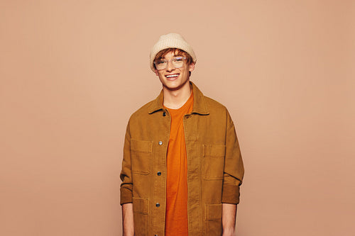 Smiling stylish man in colorful denim jacket, peach background