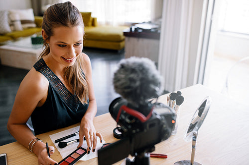 Young female vlogger recording a make-up video for her vlog.