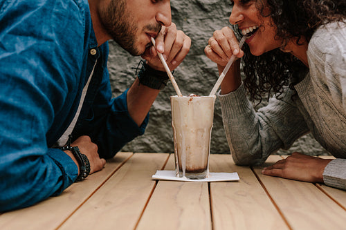 Loving couple sharing milkshake 