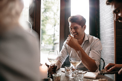 Young man smiling with friends at restaurant