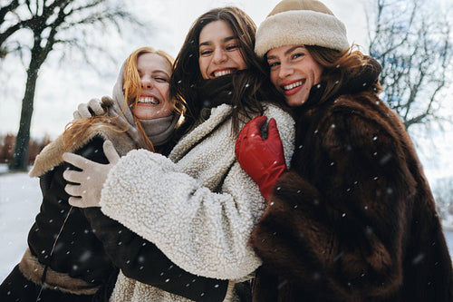 Hugging women celebrate friendship in winter snow outdoors