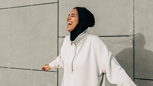Athletic Muslim woman laughing happily while working out outdoors