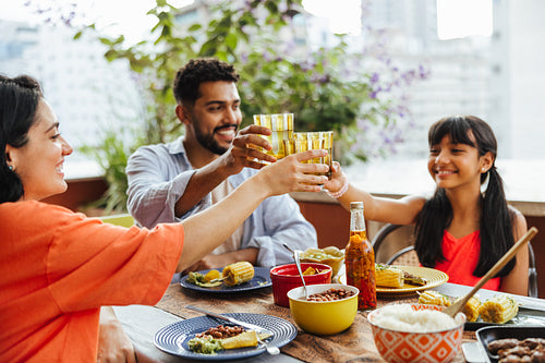 Family toasting over a meal sitting together on an outdoor terrace