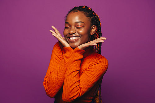 Vibrant young woman with two tone braids celebrating on a colourful purple background