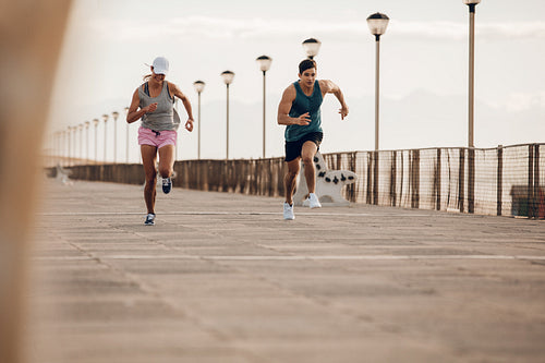 Young couple running along a seaside promenade