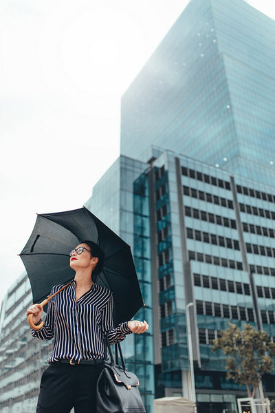 Young businesswoman on city street with umbrella