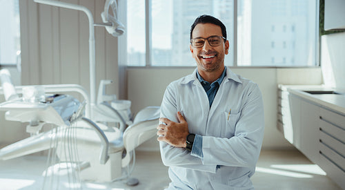 Smiling male dentist poses confidently in modern clinic