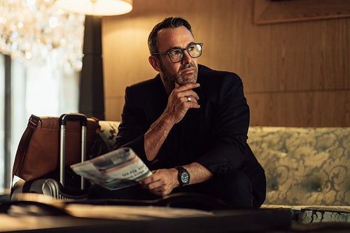 Thoughtful mature businessman sitting in hotel lobby