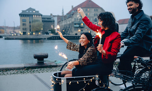 Friends celebrating together with sparklers by the waterfront in the city evening